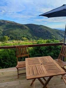 einen Holztisch und Stühle auf einer Terrasse mit einem Sonnenschirm in der Unterkunft Casa tapada da branda in Monção