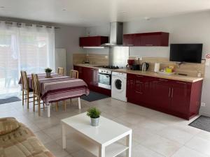 a kitchen with red cabinets and a table and a dining room at Maison de charme avec cour privée in Chaingy