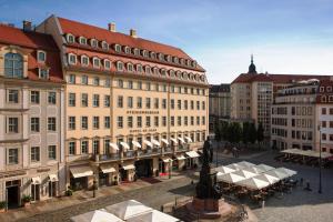 eine Stadtstraße mit Gebäuden, Tischen und einer Statue in der Unterkunft Steigenberger Hotel de Saxe in Dresden