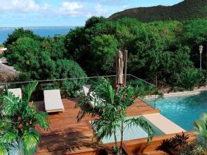 a deck with two chairs and a swimming pool at Anse Marcel: Condo de luxe avec terrasse, piscine et AC - FR-1-734-66 in Marigot +15 photos