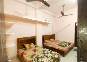a bedroom with two beds and a ceiling fan at Deviksha Home Stay in Ujjain