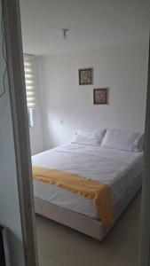 a bed in a white room with two pictures on the wall at Arriendo Apto Peña Azul La Aldea in Ricaurte +17 photos