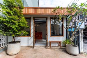 a house with a wooden door and two trees at Comfy Corner Hotel in Chiang Mai