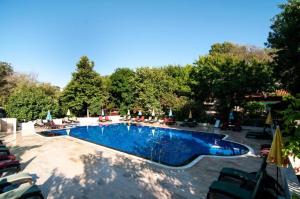 a large swimming pool with chairs and trees in the background at Fener Motel in Şile
