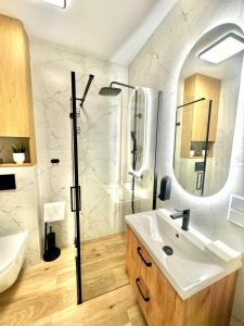 a bathroom with a sink and a shower and a mirror at LOFT APARTAMENT III NAMYSŁÓw in Namysłów +18 photos