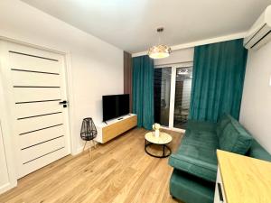 a living room with a green couch and a television at LOFT APARTAMENT III NAMYSŁÓw in Namysłów