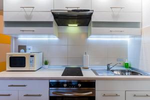 a white kitchen with a microwave and a sink at Flex SelfCheckIns 120 - Zagreb - Studio Apartment - Loggia in Zagreb