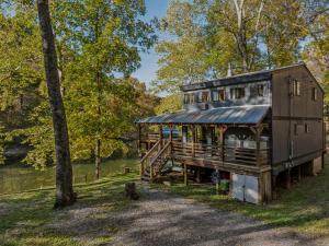 a house is sitting in the grass next to a tree at River Song Retreat - Right on the River! in Great Cacapon
