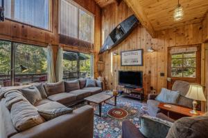 a living room with a couch and a tv at River Song Retreat - Right on the River! in Great Cacapon