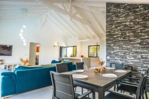a dining room with a table and a blue couch at Kisara, Villa moderne 6 pers Piscine in Saint-François