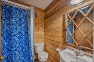 a bathroom with wooden walls and a toilet and a sink at River Song Retreat - Right on the River! in Great Cacapon +38 photos