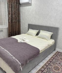 a bed with a gray headboard and pillows at Новая 1 комнатная квартира in Uralsk