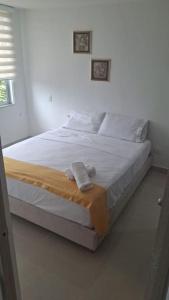 a white bed in a white room with towels on it at Arriendo Apto Peña Azul La Aldea in Ricaurte +17 photos