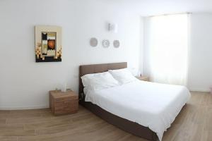 a bedroom with a white bed and a wooden floor at La Casa di Alice in Centro in Bergamo