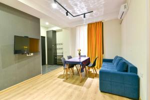 Una sala de estar con un sofá azul y una mesa. en Cozy room apartment, en Tiflis