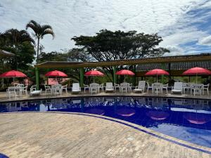 a pool with tables and chairs and red umbrellas at Ecohotel La Casona Pereira in Pereira