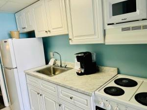 a kitchen with white cabinets and a sink and a refrigerator at Endless Ocean View Beachfront 1131 in Myrtle Beach