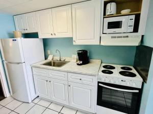 a kitchen with white cabinets and a sink and a refrigerator at Endless Ocean View Beachfront 1131 in Myrtle Beach