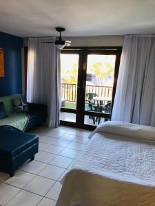 a bedroom with a bed and a couch and a balcony at Flat pé na areia Ponta Negra Natal RN 09 in Natal