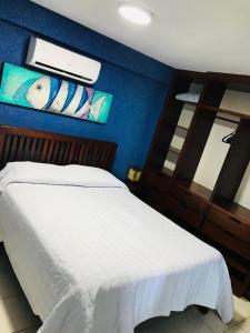 a bedroom with a white bed and a blue wall at Flat pé na areia Ponta Negra Natal RN 09 in Natal