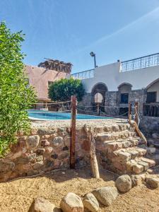 a building with a swimming pool and a stone wall at RockyHouse Homestay in Dahab