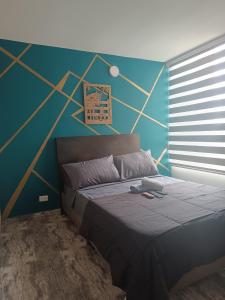 a bedroom with a bed with a blue and gold wall at Montano apartamento Ibagué in Ibagué