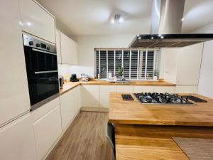 a kitchen with white cabinets and a stove top oven at The Duplex with Air Conditioning & Private Deck Area in Margate