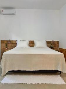 un letto bianco con lenzuola e cuscini bianchi di Casa PauBrasil a Trancoso