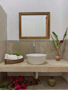 bagno con lavandino, specchio e fiori di Casa PauBrasil a Trancoso
