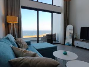 Sala de estar con sofá azul y vistas al océano en Ocean Luxury Penthouse, en Kalogrea
