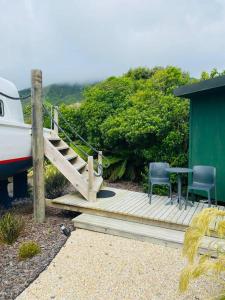 a wooden deck with two chairs and a table and a boat at Tata Sails - 200m walk to beach in Tata Beach