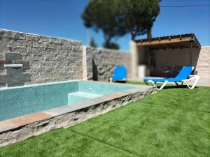 a swimming pool in a yard with two blue chairs at Villa pose in Robledillo