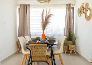 a dining room table with white chairs and an orange vase at Amaia Beach House in El Chirú