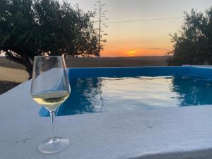 a glass of wine sitting on a table next to a pool at Canto da Planície in Conceição