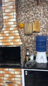 a kitchen with a grill with a blue bucket on a counter at Piscina, Churrasqueira, Ar Condicionado e 3 Vagas de Garagem in Mongaguá