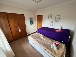 a bedroom with a bed with purple sheets and stuffed animals at CHALET CERCA DEL VIVERO y DEL MAR in Miramar