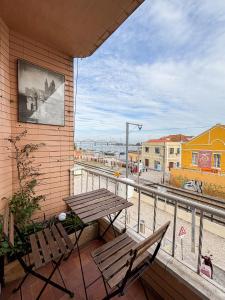 a table and chairs on a balcony with a view of a train at Aquarela do Tejo Guesthouse in Vila Franca de Xira