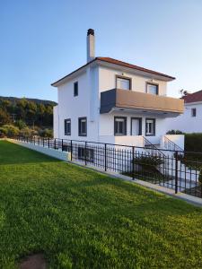 a white house with a fence in front of a yard at Villa Maritsá in Pastida