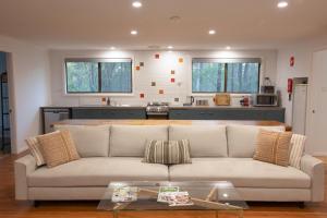 a living room with a couch and a kitchen at Pokolbin Cottages in Pokolbin