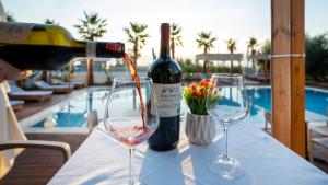 a bottle of wine is being poured into two wine glasses at Sea Queen Luxury Hotel in Vlorë