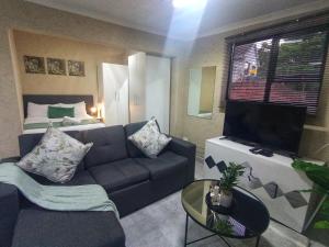 Una sala de estar con un sofá, un televisor y una cama. en 15 on Kelvin, en East London