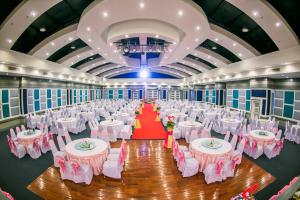 einen Bankettsaal mit weißen Tischen und rosa Stühlen in der Unterkunft Raya Grand Hotel in Nakhon Ratchasima