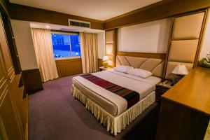 ein Hotelzimmer mit einem großen Bett und einem Fenster in der Unterkunft Raya Grand Hotel in Nakhon Ratchasima