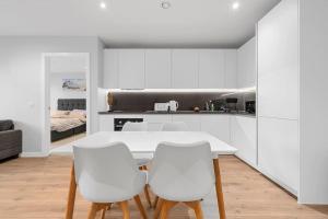 a white kitchen with a table and two white chairs at Manchester Haven Stylish Modern Apartment in Manchester