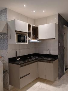 a kitchen with white cabinets and a microwave at Apto Pelourinho Centro Histórico in Salvador +9 photos