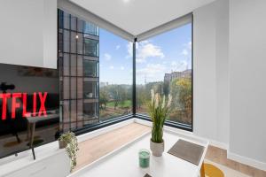 a room with a large window with a desk and a table at Manchester Haven Chique Modern Apartment in Manchester