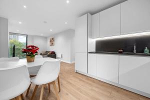 a kitchen with white cabinets and a table and chairs at Manchester Haven Chique Modern Apartment in Manchester