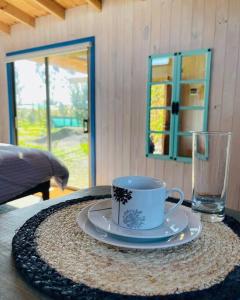 a cup and a plate on a table with a glass at Cabaña en Santo domingo, Humedal el Yali in Colegio de Bucalemu +43 photos