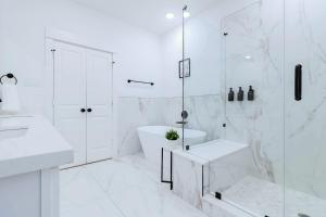 a white bathroom with a tub shower and a sink at Private Rooftop in Houston's Downtown! Pizza Oven and Skyline Views in Houston