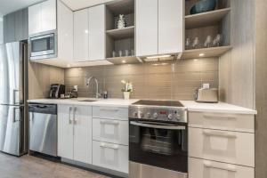 a kitchen with white cabinets and a stainless steel appliance at Modern Old Town Suite With Private Balcony in Victoria